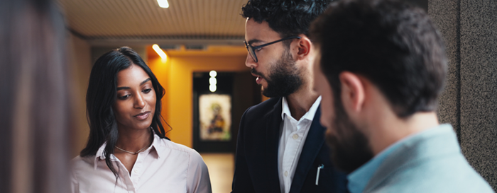 two men and one woman hold a discussion in a lobby